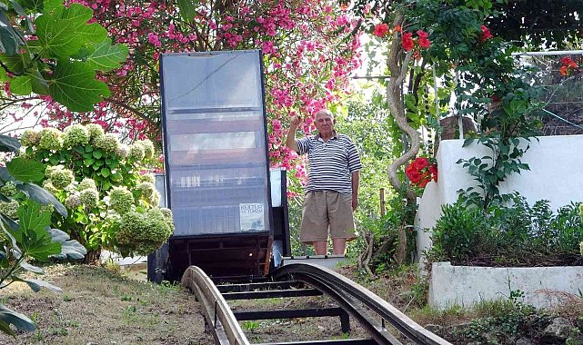 Yokuşun başındaki evine kurduğu raylı sistemle gidiyor